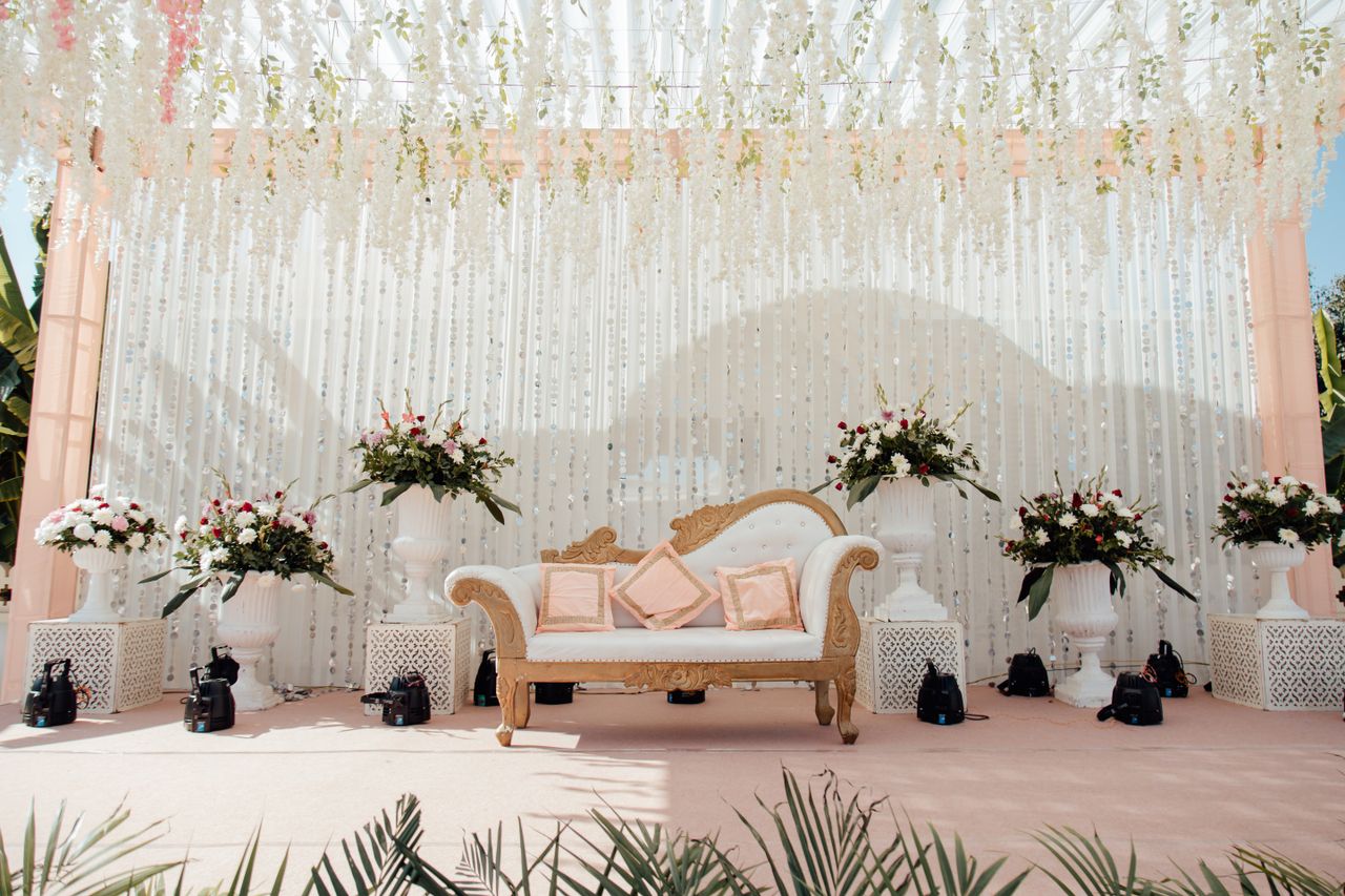 gallery-6 Luxurious outdoor wedding stage adorned with floral arrangements and elegant seating.