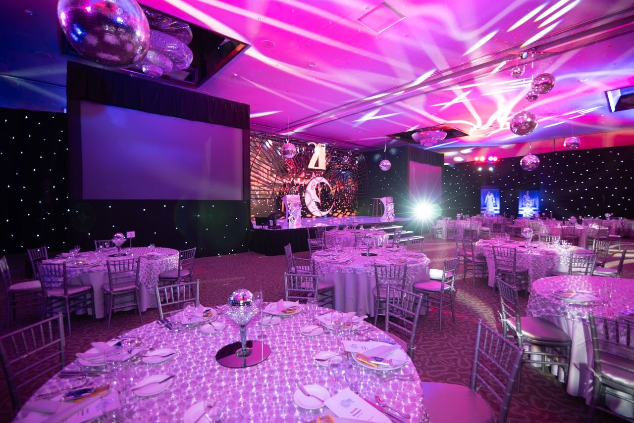 our-services-1 Elegant dinner setup in a lavish event hall with ambient lighting and disco balls.