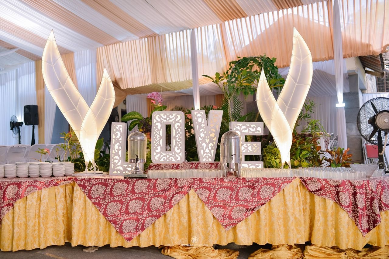 Wedding reception buffet table with LOVE sign and floral decorations, perfect for elegant events.
