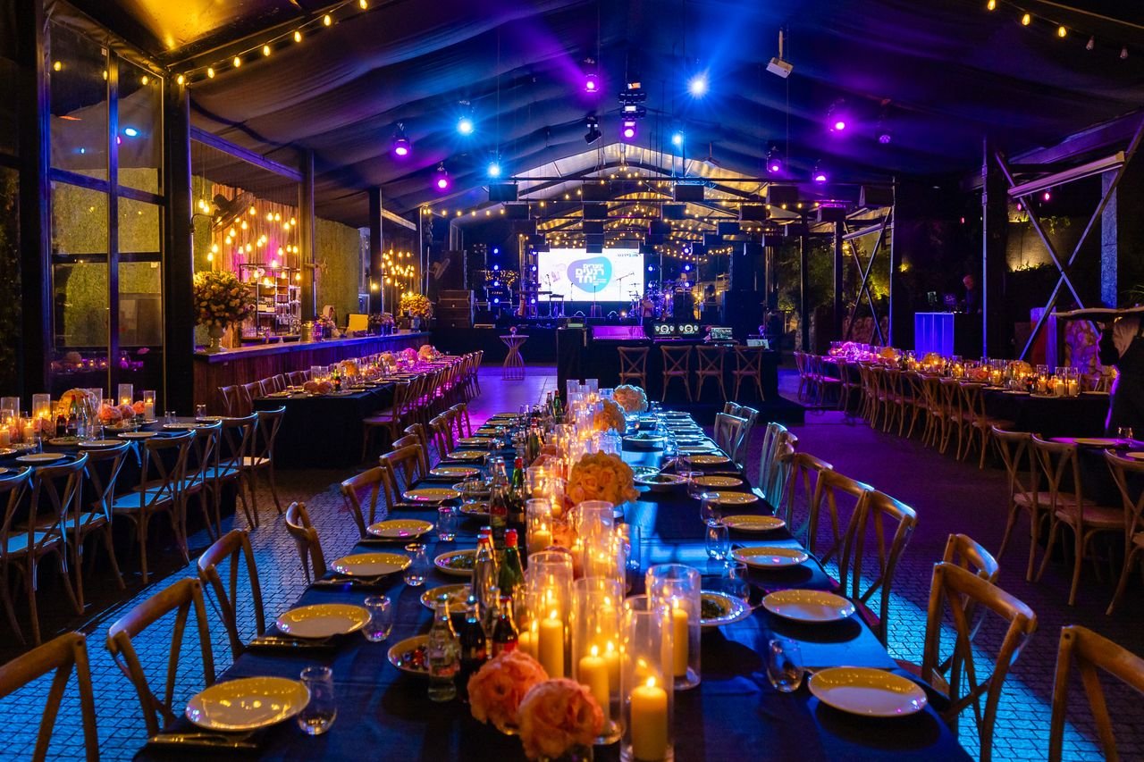 gallery-4 Luxurious evening event setup with candlelit tables and vibrant lighting in a spacious venue.